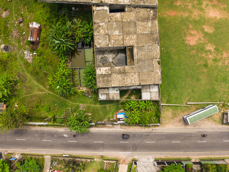 Aerial view of an old concrete building surrounded by lush tropical vegetation and a paved road with vehicles in Galle Southern Province Sri Lanka. Aerial view of an old concrete building surrounded by lush tropical vegetation and a paved road with vehicles in Galle Southern Province Sri Lanka.