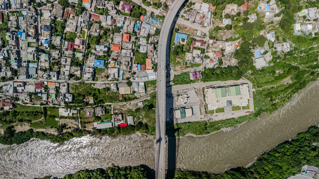 Aerial view of a bridge crossing a river with surrounding urban buildings and lush green vegetation in Muzaffarabad Azad Kashmir Pakistan. Aerial view of a bridge crossing a river with surrounding urban buildings and lush green vegetation in Muzaffarabad Azad Kashmir Pakistan.