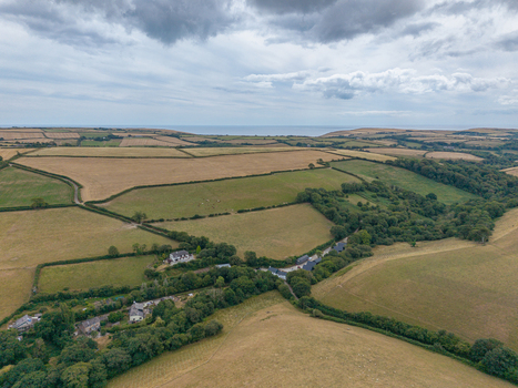 Aerial view of agricultural farmland with hedgerows tracks and harvested fields in the rural landscape of Looe Cornwall United Kingdom. Aerial view of agricultural farmland with hedgerows tracks and harvested fields in the rural landscape of Looe Cornwall United Kingdom.