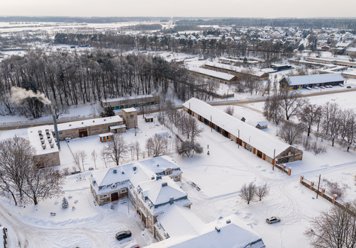Aerial view of a historic manor house and industrial buildings surrounded by snow covered fields and bare trees in Lithuania. Aerial view of a historic manor house and industrial buildings surrounded by snow covered fields and bare trees in Lithuania.