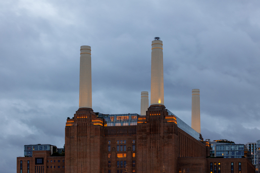 View of Battersea Power Station with its iconic chimneys and brick facade under a cloudy sky in London England United Kingdom. View of Battersea Power Station with its iconic chimneys and brick facade under a cloudy sky in London England United Kingdom.