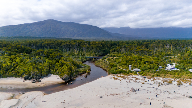 Aerial view of a river winding through a dense forest meeting the sandy beach under a cloudy sky Ship Creek Haast West Coast Region New Zealand. Aerial view of a river winding through a dense forest meeting the sandy beach under a cloudy sky Ship Creek Haast West Coast Region New Zealand.