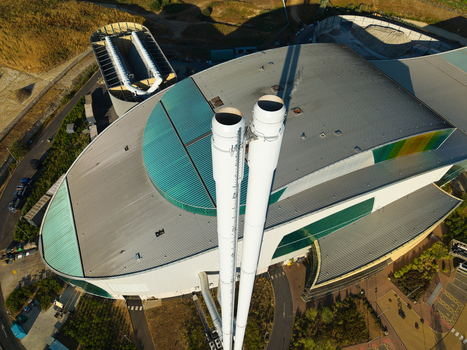 Aerial view of the Energy Recovery Facility featuring two prominent white chimneys and a modern industrial building with green roof sections in Bicester England United Kingdom.