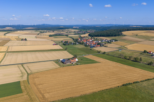 Aerial view of agricultural fields surrounding a small village with traditional houses and farm buildings in the rural landscape of Burghaun Hessen Germany. Aerial view of agricultural fields surrounding a small village with traditional houses and farm buildings in the rural landscape of Burghaun Hessen Germany.