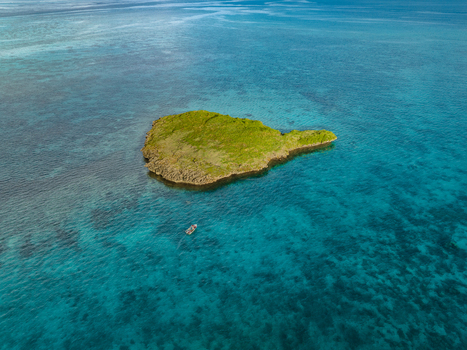 Aerial view of a verdant island nestles in the embrace of turquoise waters a lone boat adrift in its shimmering expanse Noumea New Caledonia. Aerial view of a verdant island nestles in the embrace of turquoise waters a lone boat adrift in its shimmering expanse Noumea New Caledonia.