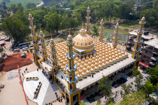 Aerial view of the ornate golden domed mosque with many minarets and blue accents shining brightly Tangail Dhaka Division Bangladesh. Aerial view of the ornate golden domed mosque with many minarets and blue accents shining brightly Tangail Dhaka Division Bangladesh.