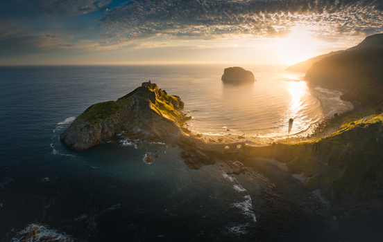 Aerial view of Gaztelugatxe islet with its winding stone bridge and hermitage under a golden sunset sky Gaztelugatxeko Doniene Basque Country Spain. Aerial view of Gaztelugatxe islet with its winding stone bridge and hermitage under a golden sunset sky Gaztelugatxeko Doniene Basque Country Spain.