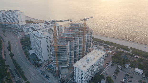 Aerial view of a high rise building under construction with cranes situated near the beach and ocean in Miami Beach Florida United States. Aerial view of a high rise building under construction with cranes situated near the beach and ocean in Miami Beach Florida United States.