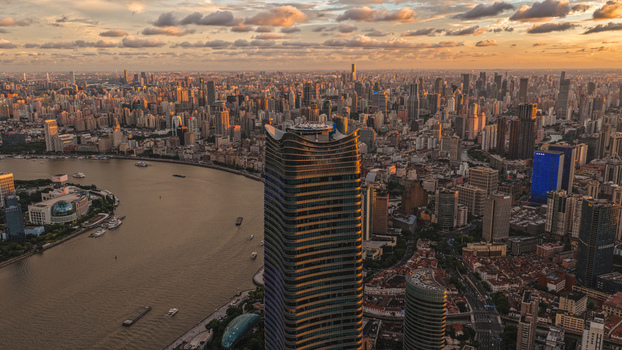 Aerial view of the dense urban skyline and the winding Huangpu River during a golden sunset with scattered clouds over Shanghai Shanghai China. Aerial view of the dense urban skyline and the winding Huangpu River during a golden sunset with scattered clouds over Shanghai Shanghai China.