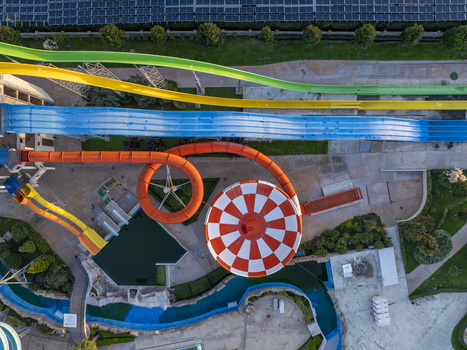 Aerial view of a vibrant water park featuring colorful water slides a large orange and white bowl slide and a winding lazy river in Bulgaria. Aerial view of a vibrant water park featuring colorful water slides a large orange and white bowl slide and a winding lazy river in Bulgaria.
