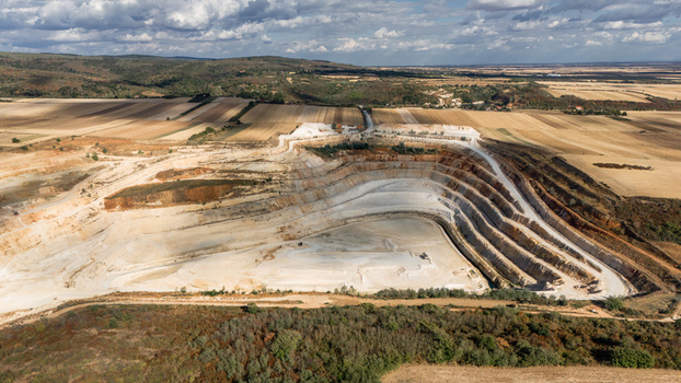 Aerial view of the Besenovo quarry showing terraced excavation pits surrounded by vast agricultural fields and rolling hills under a cloudy sky in Besenovo Vojvodina Serbia. Aerial view of the Besenovo quarry showing terraced excavation pits surrounded by vast agricultural fields and rolling hills under a cloudy sky in Besenovo Vojvodina Serbia.