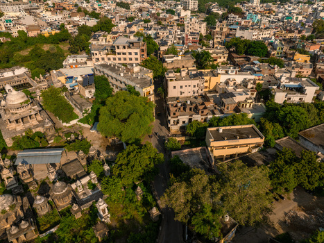 Aerial view of the historic city of Udaipur with its dense urban rooftops traditional architecture lush green trees and narrow streets Udaipur Rajasthan India.