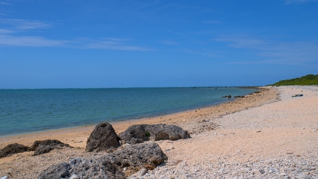 View of the rocky shoreline and turquoise waters of Shiraho Beach under a clear blue sky in Ishigaki Okinawa Japan.
