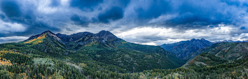 Aerial view of the Alpine Loop Scenic Byway featuring vibrant autumn foliage rugged mountain peaks and dense pine forests under a dramatic cloudy sky in Utah County Utah United States. Aerial view of the Alpine Loop Scenic Byway featuring vibrant autumn foliage rugged mountain peaks and dense pine forests under a dramatic cloudy sky in Utah County Utah United States.