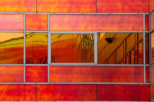 View of a vibrant orange and red facade reflecting a distorted cityscape creating a surreal and abstract composition La Defense Flevoland Netherlands. View of a vibrant orange and red facade reflecting a distorted cityscape creating a surreal and abstract composition La Defense Flevoland Netherlands.