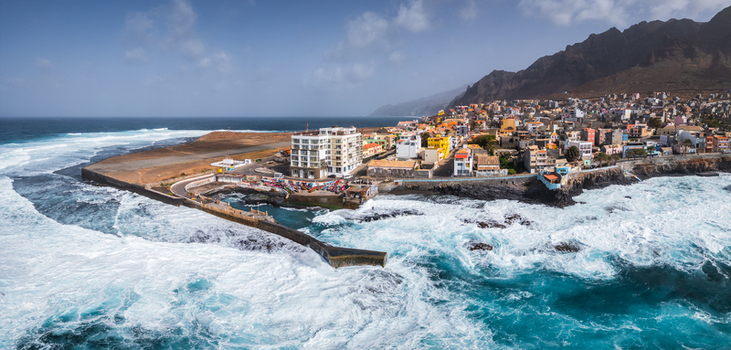 Aerial view of Ponta do Sol on Santo Antao featuring colorful buildings a breakwater and waves crashing against the shore in Ponta do Sol Ribeira Grande Cabo Verde.