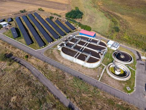 Aerial view of sewage treatment plant with circular sedimentation tanks and an adjacent solar panel array in a rural landscape in Targu Secuiesc Covasna County Romania.