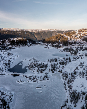 Aerial view of Gaustablikk Fjellresort surrounded by a frozen lake snow covered pine forests and rugged mountains in the winter landscape of Rjukan Telemark Norway. Aerial view of Gaustablikk Fjellresort surrounded by a frozen lake snow covered pine forests and rugged mountains in the winter landscape of Rjukan Telemark Norway.