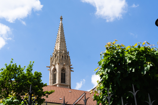 View of the ornate Gothic spire of St. Martin s Cathedral rising above green trees under a blue sky in Bratislava Bratislava Region Slovakia. View of the ornate Gothic spire of St. Martin s Cathedral rising above green trees under a blue sky in Bratislava Bratislava Region Slovakia.