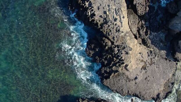 Aerial view of waves crashing on the rocky coast Indonesia.