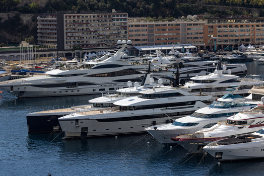 Aerial view of luxury superyachts docked in the harbor of Monaco City with modern buildings and lush hills in the background Monaco Monaco.