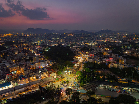 Aerial view of the illuminated cityscape at dusk featuring dense urban architecture glowing street lights and distant hills under a twilight sky in Udaipur Rajasthan India. Aerial view of the illuminated cityscape at dusk featuring dense urban architecture glowing street lights and distant hills under a twilight sky in Udaipur Rajasthan India.