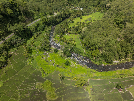 Aerial view of the river winding through lush green rice terraces and tropical vegetation in Flores East Nusa Tenggara Indonesia. Aerial view of the river winding through lush green rice terraces and tropical vegetation in Flores East Nusa Tenggara Indonesia.