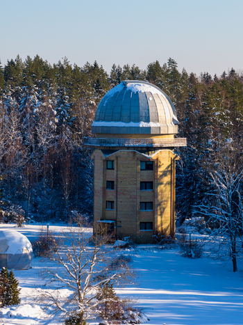 Aerial view of the Moletai Astronomical Observatory tower with a snow covered dome surrounded by a winter pine forest in Kulionys Utenos apskritis Lithuania. Aerial view of the Moletai Astronomical Observatory tower with a snow covered dome surrounded by a winter pine forest in Kulionys Utenos apskritis Lithuania.