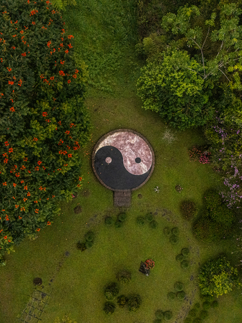 Aerial view of a circular Yin Yang symbol set in a lush garden surrounded by flowering trees and green foliage in Cinchona Alajuela Province Costa Rica. Aerial view of a circular Yin Yang symbol set in a lush garden surrounded by flowering trees and green foliage in Cinchona Alajuela Province Costa Rica.