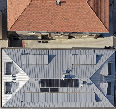 Aerial view of a modern building with a grey metal roof and solar panels adjacent to a traditional building with a red tiled roof in Istanbul Istanbul Turkiye.