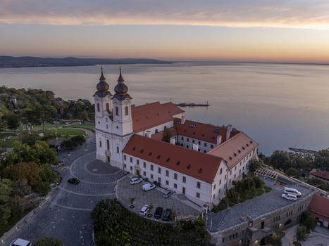 Aerial view of Tihany Abbey with its iconic twin towers and red tiled roofs overlooking the calm waters of Lake Balaton at sunset in Tihany Hungary. Aerial view of Tihany Abbey with its iconic twin towers and red tiled roofs overlooking the calm waters of Lake Balaton at sunset in Tihany Hungary.