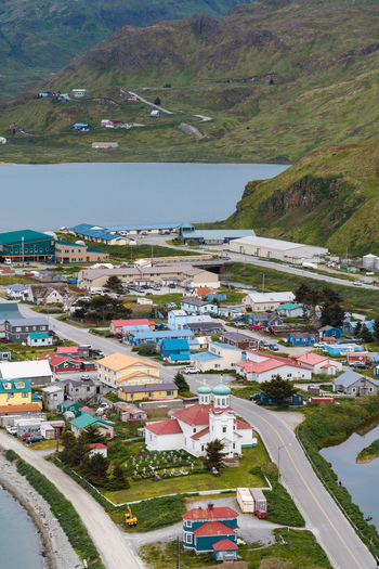Aerial view of the historic Holy Ascension of Our Lord Cathedral surrounded by colorful houses winding roads and green hills in Unalaska Alaska United States.