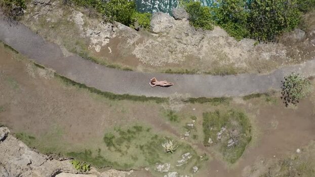 Aerial view of a woman lying on a coastal path Indonesia. Aerial view of a woman lying on a coastal path Indonesia.