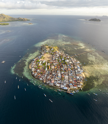 Aerial view of Pulau Mesa a dense island village surrounded by coral reefs and clear turquoise waters with small fishing boats in Kecamatan Komodo Nusa Tenggara Timur Indonesia. Aerial view of Pulau Mesa a dense island village surrounded by coral reefs and clear turquoise waters with small fishing boats in Kecamatan Komodo Nusa Tenggara Timur Indonesia.