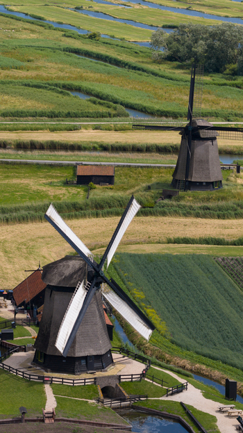 Aerial view of De Museummolen windmills surrounded by lush green fields winding canals and historic Dutch landscape in Schermerhorn Noord Holland Netherlands. Aerial view of De Museummolen windmills surrounded by lush green fields winding canals and historic Dutch landscape in Schermerhorn Noord Holland Netherlands.