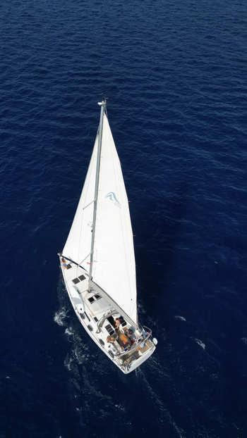Croatia 22 August 2023 Aerial view of a white sailboat with people on deck cruising through the deep blue waters of the Adriatic Sea near Hvar. Croatia 22 August 2023 Aerial view of a white sailboat with people on deck cruising through the deep blue waters of the Adriatic Sea near Hvar.