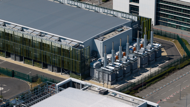 Aerial view of the Kao Data campus featuring modern industrial architecture rows of cooling units and fenced perimeter in Harlow England United Kingdom. Aerial view of the Kao Data campus featuring modern industrial architecture rows of cooling units and fenced perimeter in Harlow England United Kingdom.