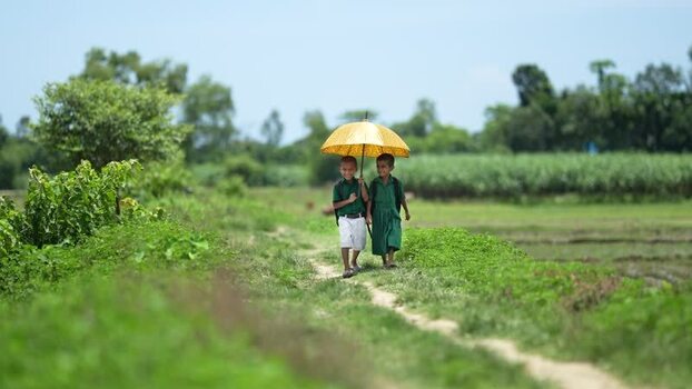 View of school children walking with an umbrella in Bogura Bangladesh.