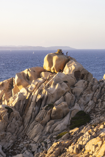 View of the unique granite rock formations of Capo Testa with people standing on the summit overlooking the Mediterranean Sea Capo Testa Sardegna Italy.