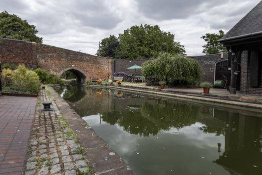 View of the historic Coventry Canal Basin with its brick bridge calm water and surrounding greenery in Coventry England United Kingdom.