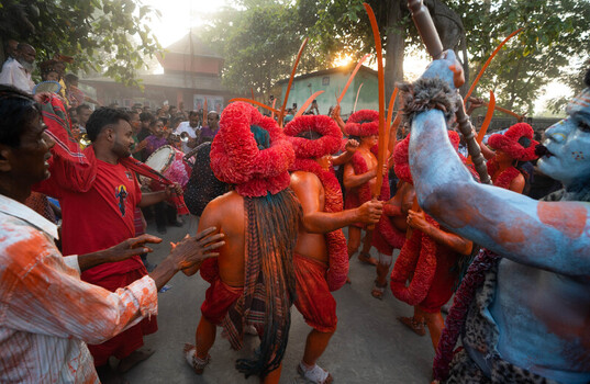 Munshiganj Bangladesh 13 April 2025 View of vibrant performers in fiery red and orange body paint their elaborate headwear dancing in golden dusty light. Munshiganj Bangladesh 13 April 2025 View of vibrant performers in fiery red and orange body paint their elaborate headwear dancing in golden dusty light.