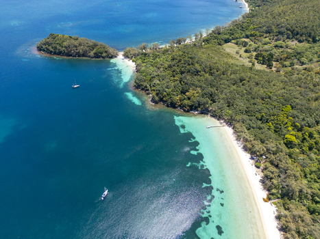 Aerial view of the lush tropical coastline of Guanaja island with turquoise waters and a white sand beach in Guanaja Bay Islands Department Honduras. Aerial view of the lush tropical coastline of Guanaja island with turquoise waters and a white sand beach in Guanaja Bay Islands Department Honduras.
