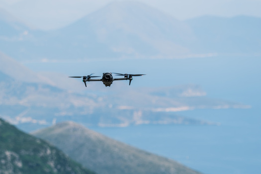 View of a quadcopter drone flying in the air with the coastal mountains and the sea in the background from Panorama Llogora Himare Qarku i Vlores Albania.