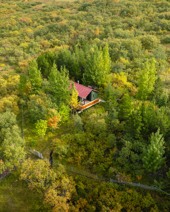Aerial view of a solitary cabin nestled amidst the vibrant tapestry of autumn foliage a serene escape in nature s embrace Egilsstaðir Iceland. Aerial view of a solitary cabin nestled amidst the vibrant tapestry of autumn foliage a serene escape in nature s embrace Egilsstaðir Iceland.
