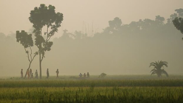 View of people in a misty rural field in Bogura Bangladesh.