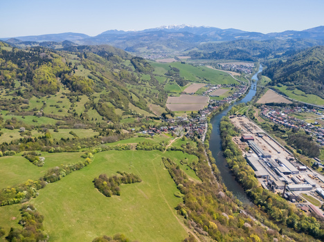Aerial view of the Orava river winding through a lush green valley with a small village and distant mountains Oravsky Podzamok Zilina Region Slovakia. Aerial view of the Orava river winding through a lush green valley with a small village and distant mountains Oravsky Podzamok Zilina Region Slovakia.