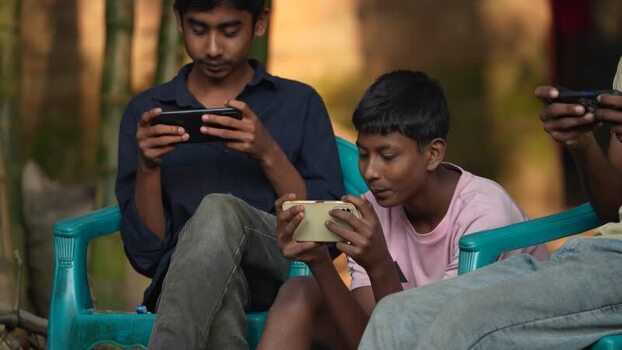 View of young boys playing games on smartphones in Bogura Bangladesh. View of young boys playing games on smartphones in Bogura Bangladesh.