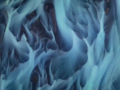 Aerial view of abstract glacial river patterns with blue water and volcanic silt in Iceland.