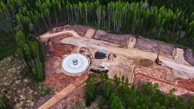 Aerial view of a wind turbine foundation under construction in a forest clearing with heavy machinery and earthworks in Latvija. Aerial view of a wind turbine foundation under construction in a forest clearing with heavy machinery and earthworks in Latvija.
