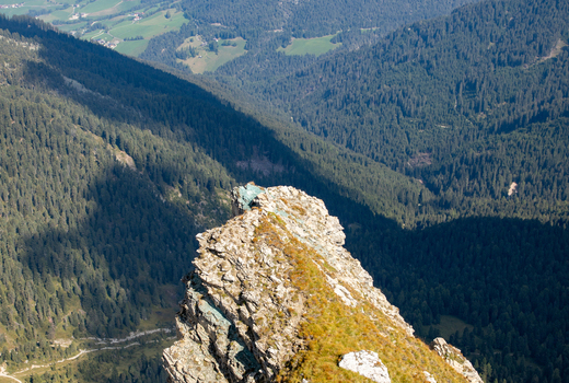 Aerial view of the rugged rocky peak of the Dolomites rising above the dense pine forests of the valley in Rocca Pietore Veneto Italy.